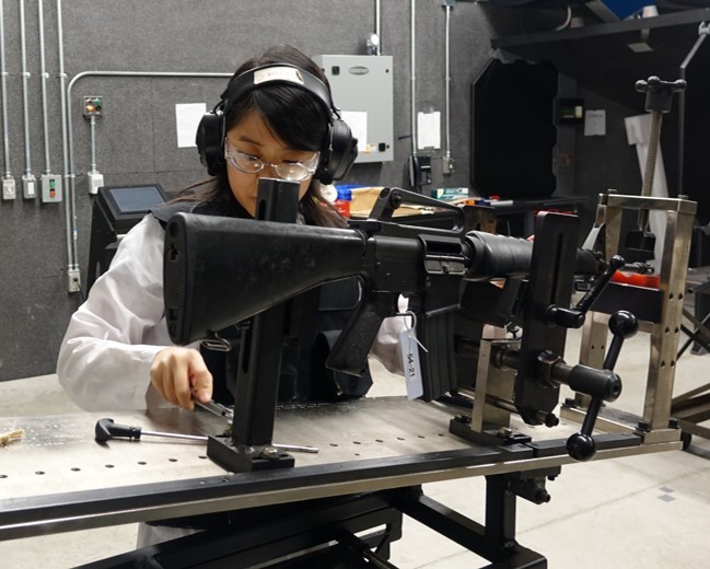 scientist mounting a rifle in a secure holding device prior to test firing